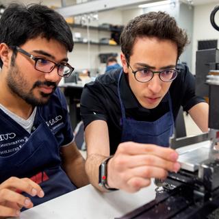 Two male students looking intently at a lab instrument